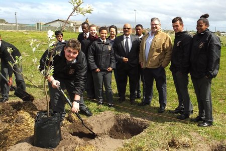 Marc John Hayes (Gr 11) van Gansbaai Academia is besig om ‘n boom te plant, met Riaan Conradie (AfriForum) 3de van regs en Tommy Wilson (skoolhoof) langs hom